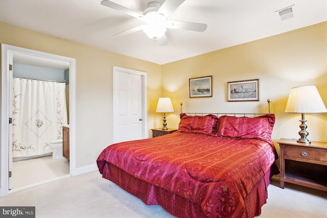 bedroom with light colored carpet, ensuite bath, and ceiling fan