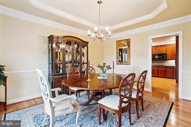 dining area with a raised ceiling, crown molding, light hardwood / wood-style flooring, and a chandelier