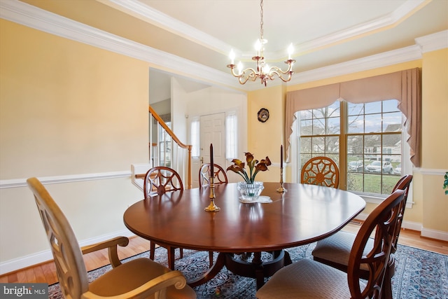 dining area featuring a chandelier, wood-type flooring, ornamental molding, and a tray ceiling