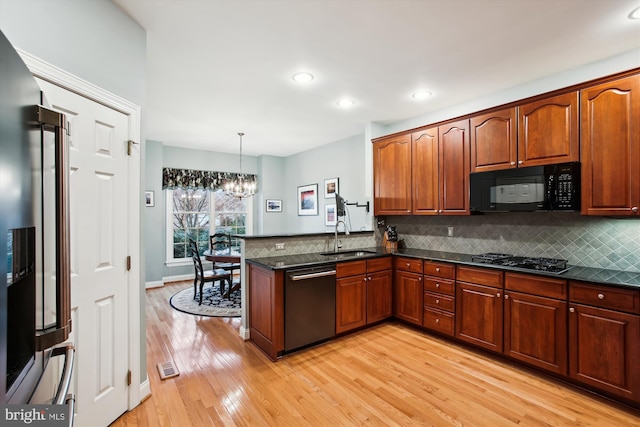 kitchen with an inviting chandelier, sink, decorative light fixtures, kitchen peninsula, and stainless steel appliances