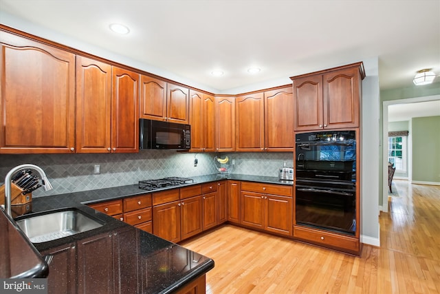 kitchen with backsplash, sink, black appliances, and light hardwood / wood-style flooring