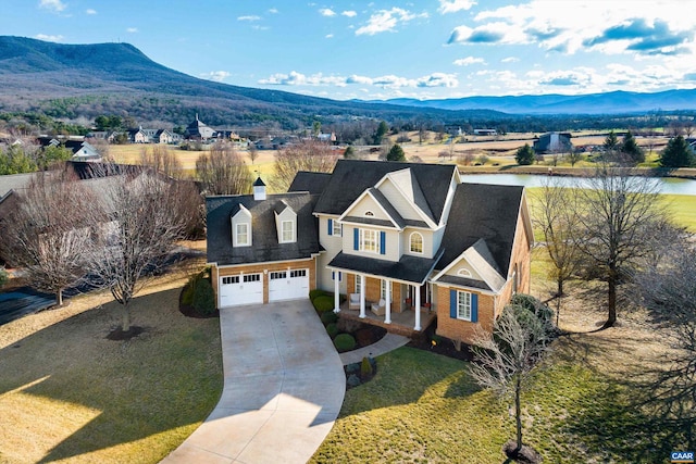 view of front facade featuring a water and mountain view, a front yard, and a garage