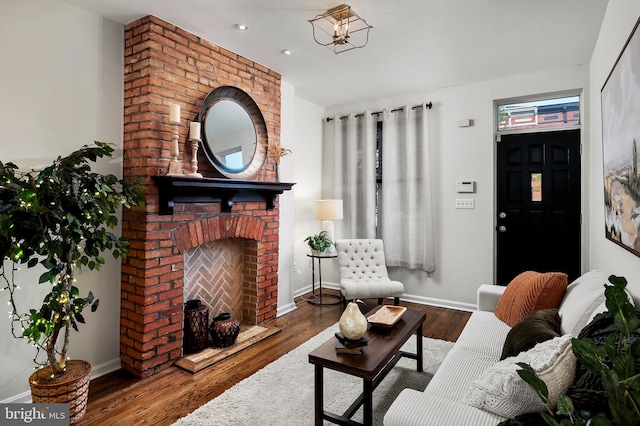 living room featuring hardwood / wood-style flooring, a brick fireplace, and a notable chandelier