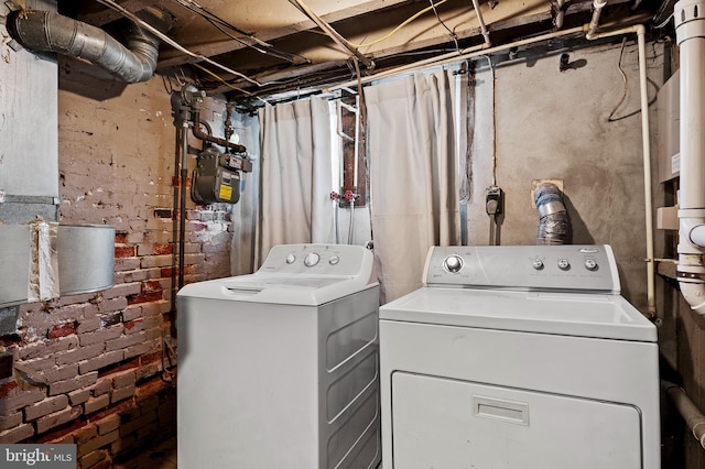 washroom featuring brick wall and independent washer and dryer