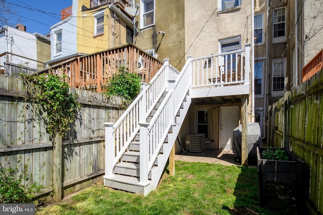 back of property featuring a wooden deck, a lawn, and central air condition unit