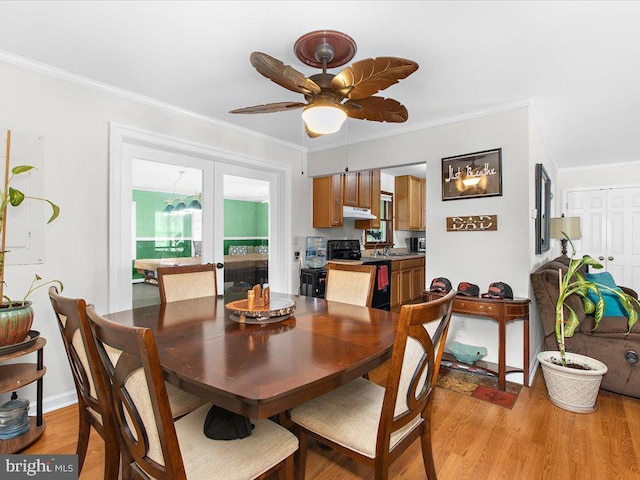 dining space featuring ceiling fan, sink, ornamental molding, and light wood-type flooring