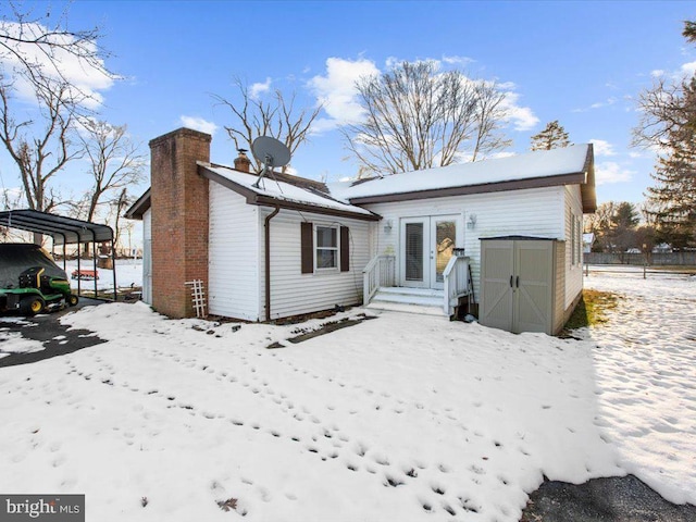 snow covered house with a shed and a carport