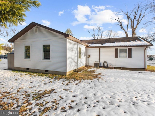 snow covered back of property featuring central AC unit