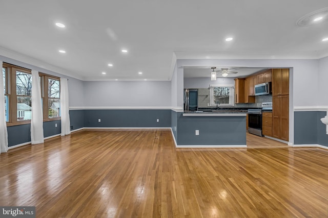 kitchen with sink, a kitchen breakfast bar, kitchen peninsula, stainless steel appliances, and light hardwood / wood-style flooring