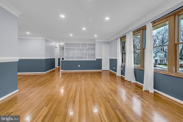 unfurnished living room featuring ornamental molding and light hardwood / wood-style flooring