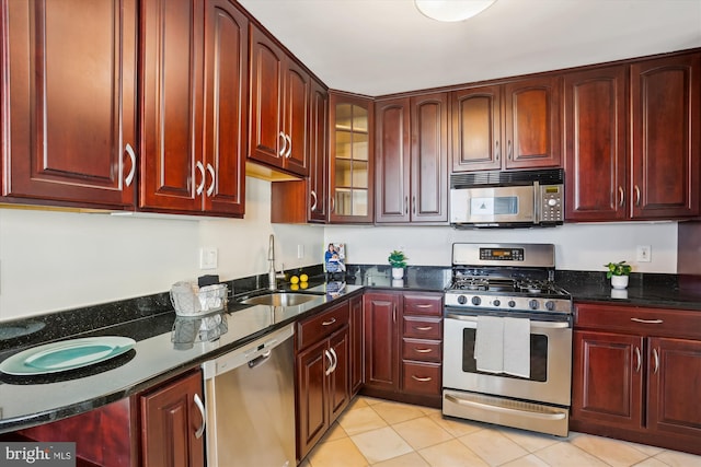 kitchen featuring stainless steel appliances, light tile patterned flooring, sink, and dark stone counters