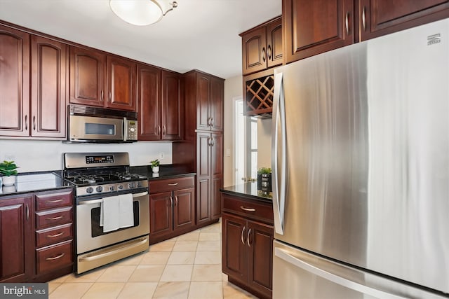 kitchen featuring dark stone countertops, appliances with stainless steel finishes, and light tile patterned floors