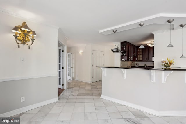 kitchen with decorative light fixtures, dark brown cabinets, a breakfast bar, and kitchen peninsula