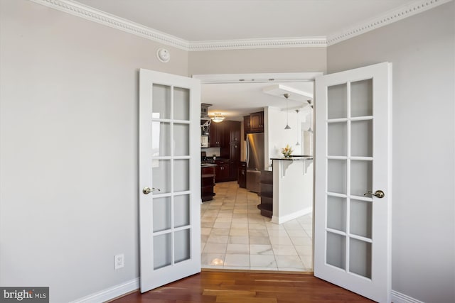 empty room featuring ornamental molding, french doors, and light wood-type flooring