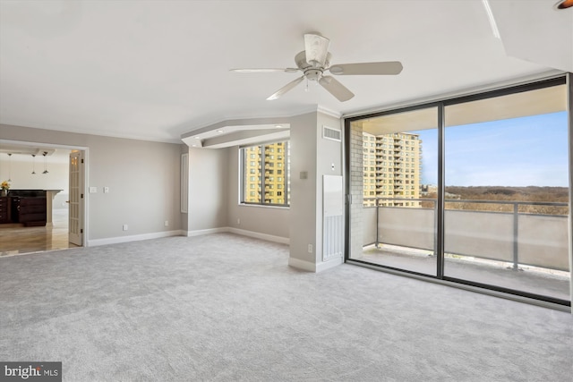 unfurnished living room with floor to ceiling windows, ornamental molding, light colored carpet, and ceiling fan