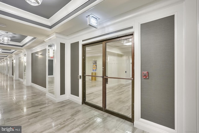 corridor with crown molding, ornate columns, a tray ceiling, and light wood-type flooring