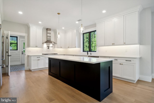 kitchen with white cabinets, wall chimney exhaust hood, and decorative light fixtures