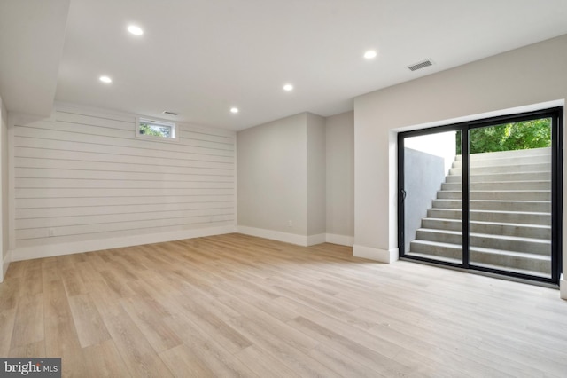 interior space with light wood-type flooring, a healthy amount of sunlight, and wood walls