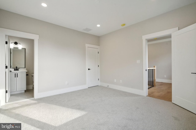 unfurnished bedroom featuring recessed lighting, visible vents, light carpet, a sink, and baseboards