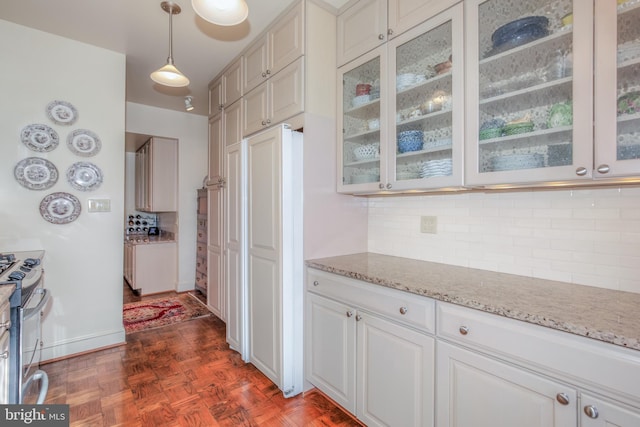 kitchen with dark parquet flooring, light stone countertops, stainless steel gas range, decorative light fixtures, and decorative backsplash