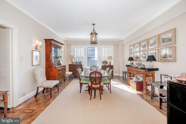 dining room with a chandelier, ornamental molding, and light parquet floors