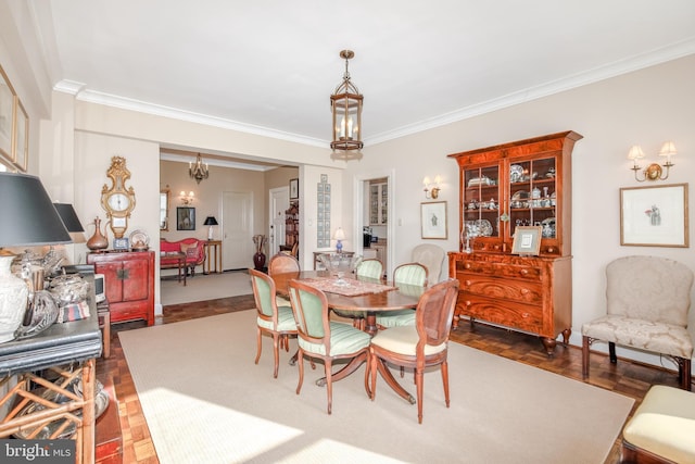 dining area with crown molding, dark parquet floors, and an inviting chandelier