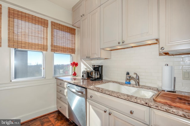 kitchen featuring dark hardwood / wood-style flooring, tasteful backsplash, light stone counters, stainless steel dishwasher, and sink