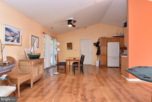 dining area with ceiling fan, light hardwood / wood-style floors, and vaulted ceiling