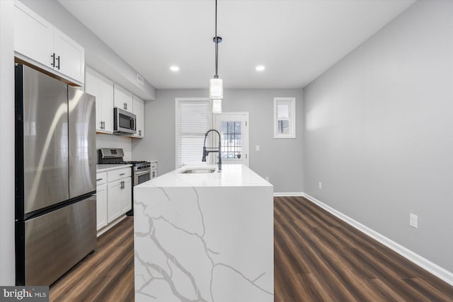 kitchen with pendant lighting, a center island with sink, sink, appliances with stainless steel finishes, and white cabinetry