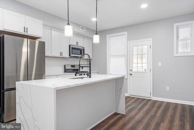 kitchen with pendant lighting, a center island with sink, white cabinets, and stainless steel appliances