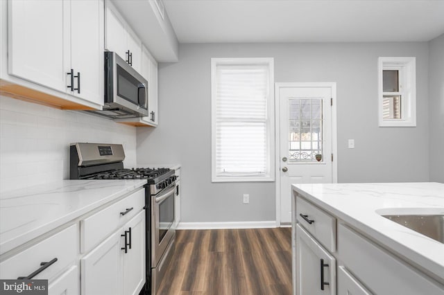 kitchen with backsplash, dark wood-type flooring, white cabinets, appliances with stainless steel finishes, and light stone counters