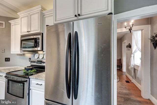 kitchen featuring white cabinets, appliances with stainless steel finishes, dark hardwood / wood-style floors, and light stone counters