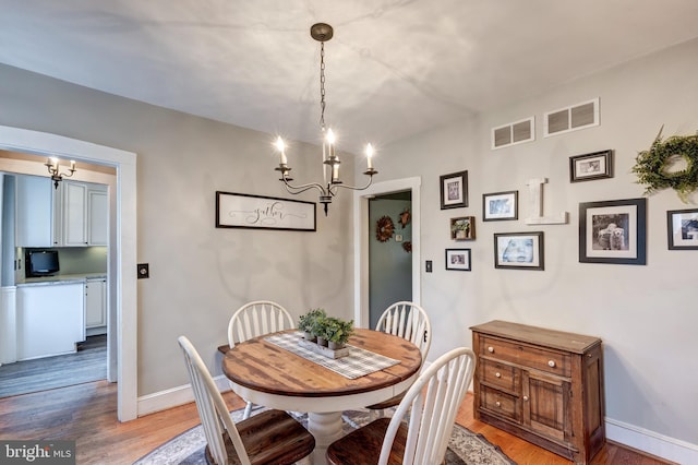 dining space featuring hardwood / wood-style floors and an inviting chandelier