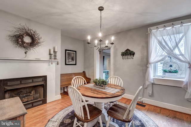 dining area with light hardwood / wood-style floors and an inviting chandelier