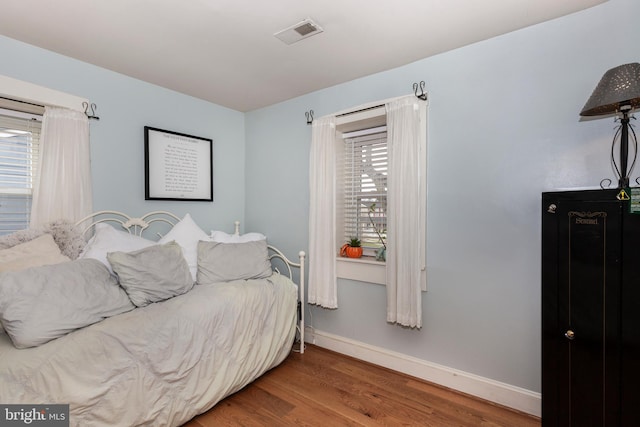 bedroom with hardwood / wood-style floors and multiple windows