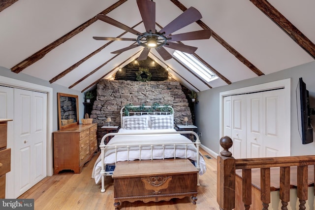 bedroom featuring vaulted ceiling with skylight, ceiling fan, and light hardwood / wood-style flooring