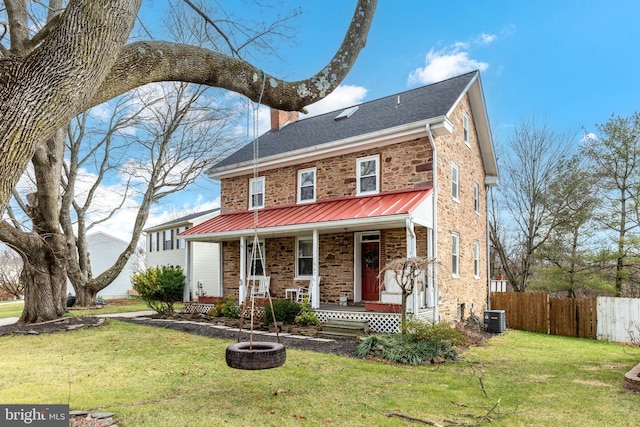 view of front of property with covered porch, central AC, and a front lawn