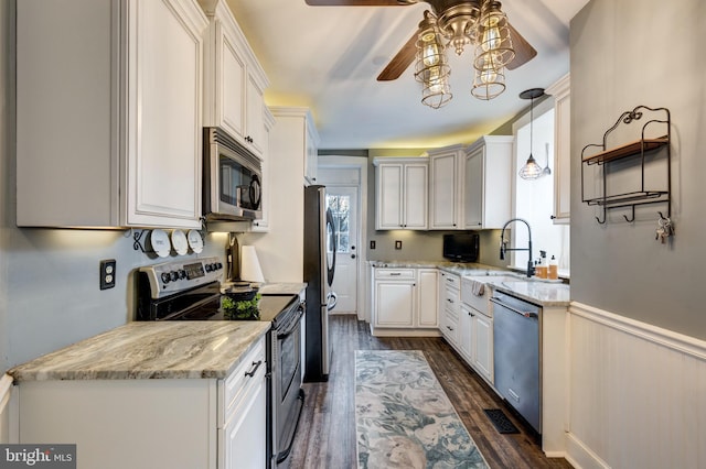 kitchen with white cabinets, sink, decorative light fixtures, light stone counters, and stainless steel appliances