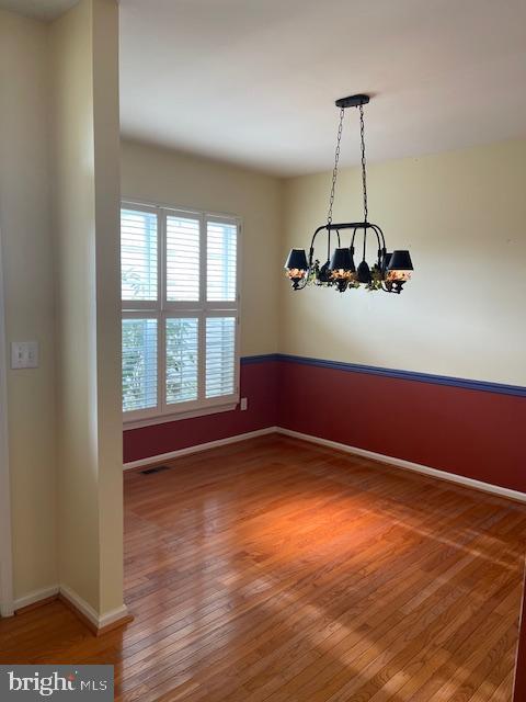 spare room with a notable chandelier and hardwood / wood-style flooring