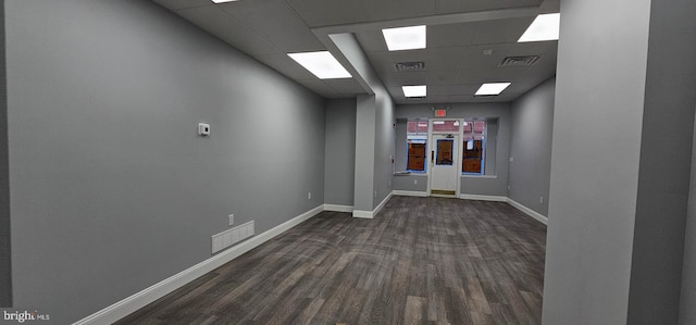 corridor with a drop ceiling and dark wood-type flooring