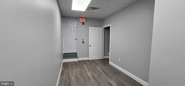 hall with a paneled ceiling and dark wood-type flooring