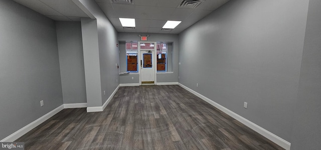 spare room with dark hardwood / wood-style flooring and a drop ceiling