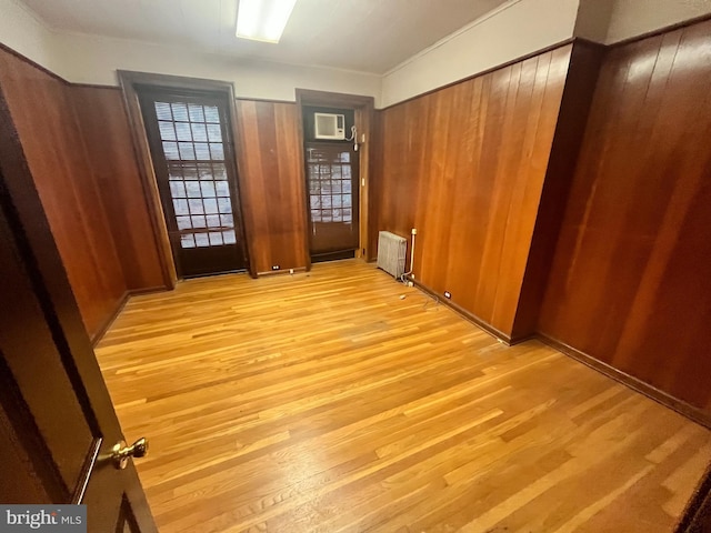 empty room featuring radiator, wood walls, and light hardwood / wood-style flooring