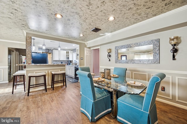 dining area with hardwood / wood-style flooring and crown molding