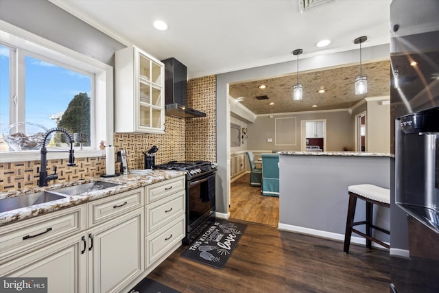 kitchen with pendant lighting, white cabinets, black range with gas stovetop, sink, and wall chimney exhaust hood