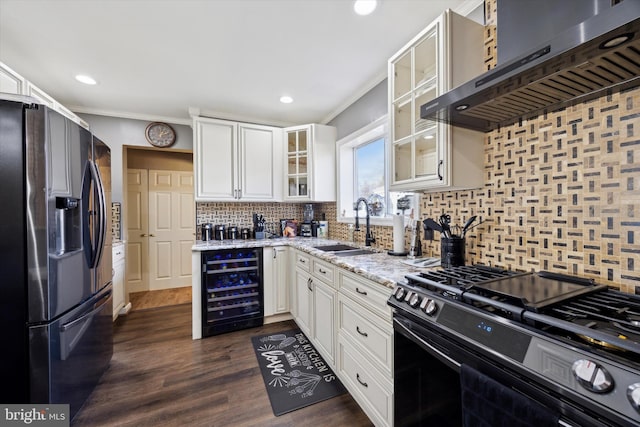 kitchen with black gas range, sink, beverage cooler, wall chimney range hood, and refrigerator with ice dispenser