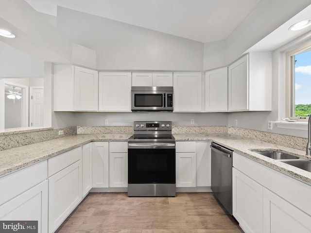 kitchen featuring white cabinets, sink, light hardwood / wood-style flooring, light stone countertops, and stainless steel appliances