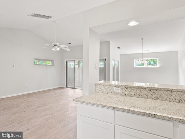 kitchen with white cabinetry, ceiling fan, light stone counters, pendant lighting, and lofted ceiling