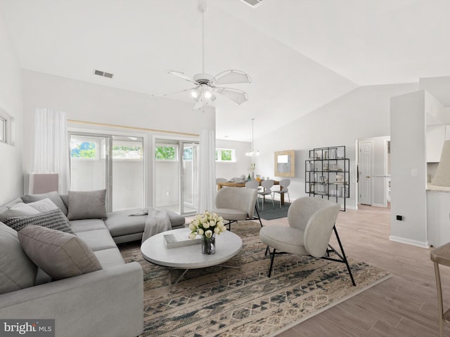 living room featuring ceiling fan with notable chandelier, light hardwood / wood-style floors, and high vaulted ceiling