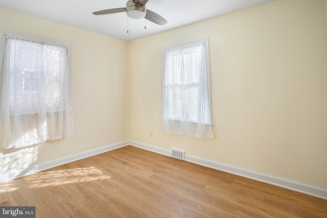 spare room featuring ceiling fan, a healthy amount of sunlight, and light wood-type flooring